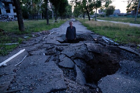 Der Anwohner Viktor Shevchenko steht in einem Krater, den die russischen Bomben bei ihrem Angriff auf die Stadt Charkiw am 1. Juli 2022 hinterlassen haben