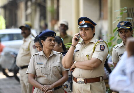 Zwei Polizistinnen stehen in heller Uniform nebeneinander; die rechte telefoniert