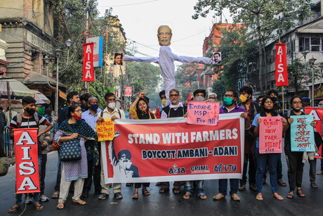 Rund 20 Menschen stehen auf einer Straße mit Schildern nebeneinander, die zum Boykott von Adani aufrufen; einer der Demonstranten hält außerdem eine große Puppe hoch, die aussieht wie der indische Premierminister Narendra Modi