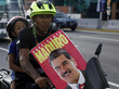 Ein Mann fährt auf einem Motorrad und trägt dabei ein Wahlplakat vom Präsidenten Nicolas Maduro mit sich.