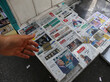 Eine Hand zeigt auf Zeitungen, die auf einem Tisch liegen. Auf den Titelseiten sind die beiden genannten Präsidentschaftskandidaten zu sehen.